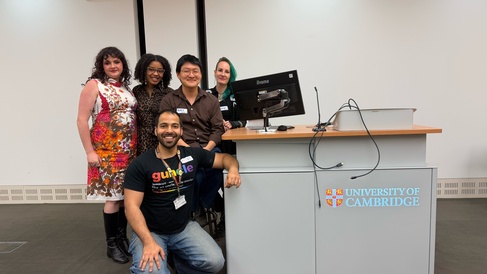 A photo of five PhD students standing on front of a lecture desk, at the Institute of Criminology.