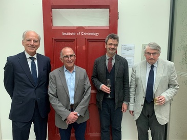 Current and former directors and speaker standing in front of the red door from the old IoC building