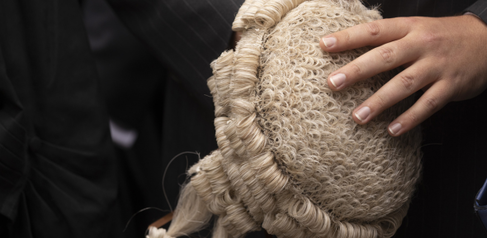 A photo of a judge's wig, being held in the hands of a judge.