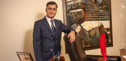 A photograph of Sidharth Luthra standing behind his desk.