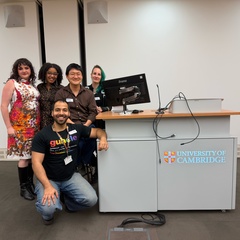 A photo of five PhD students standing on front of a lecture desk, at the Institute of Criminology.