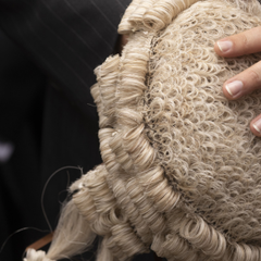 A photo of a judge's wig, being held in the hands of a judge.