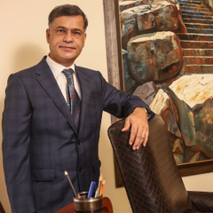 A photograph of Sidharth Luthra standing behind his desk.